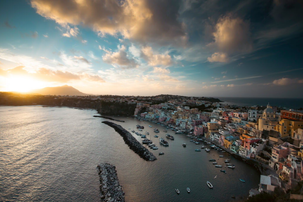 View of the Port of Corricella with lots of colorful houses in the sunset, Procida Island, Italy.